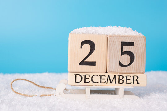 The 25th of december concept its christmas day. Close up photo of calendar showing date of christmas on wooden white sledges and blue sky