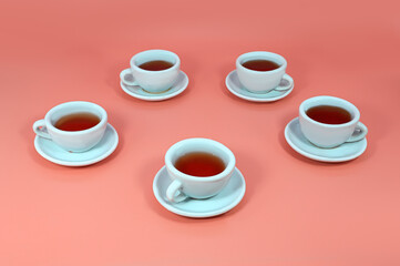 Toy cups with saucers and tea on a pink background