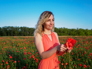 Young girl in a red dress in a poppy field
