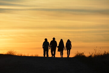 group silhouette walking into the sunset