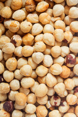 Closeup of a plate full of peeled hazelnuts
and with skin. Organic textures as a background. Vegan food.