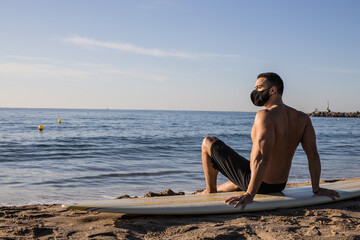 Surfer sitting on surf board with protective mask