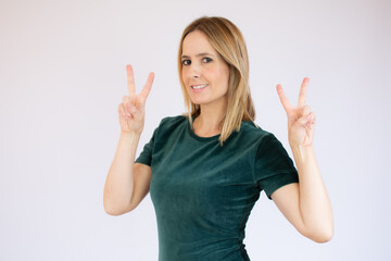 Fototapeta na wymiar Portrait of a smiling happy woman showing victory sign and looking at camera isolated on the white background