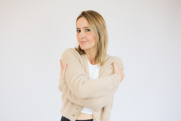 Portrait of a pretty young woman in casual sweater hugging herself. Concept of selfish emotion.