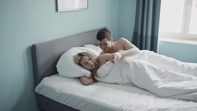 Side view of young married couple experiencing stress and anxiety about their sexual relationship. Blonde woman with migraine or headache denies brunette man sex. Unhappy girl is angry with guy.