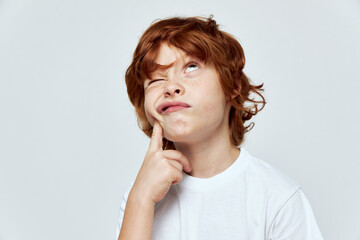 The red-haired boy looks upward is plotting something wrong white t-shirt