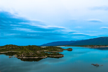 Fototapeta na wymiar Vista de unas pequeñas islas de tierra rodeadas por un lago junto a las montañas