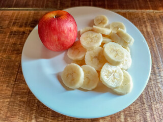 An apple and a sliced banana on wooden background