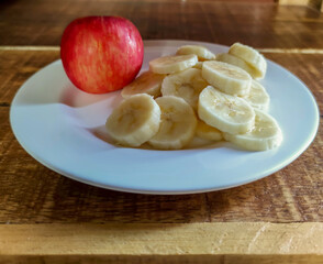 Naklejka na ściany i meble An apple and a sliced banana on wooden background