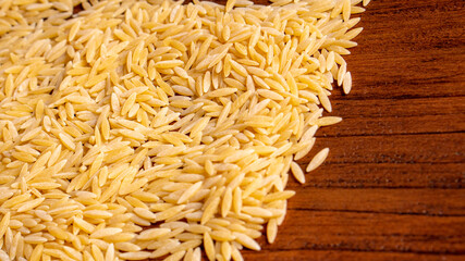 Raw dry uncooked Orza Risoni pasta spaghetti noodle on white bowl wooden background for basil tomato pesto sauce Homemade Italian food organic whole wheat vegan spaghetti for a healthy meal