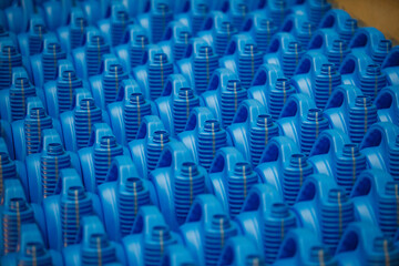 Obraz premium Blue plastic motor oil canisters on conveyor line. Close-up photo with blurred background.