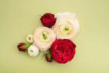 Ranunculus and red rose floral flat lay on green background