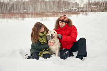 portrait of a young couple with a dog on a winter walk. man and woman with labrador