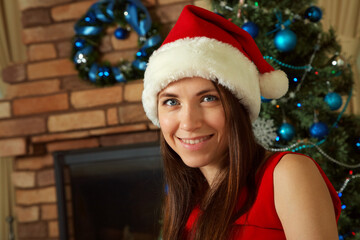 woman in santa hat with gift box near Christmas tree.