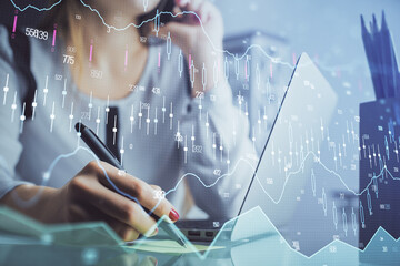 Double exposure of woman hands typing on computer and financial graph hologram drawing. Stock...
