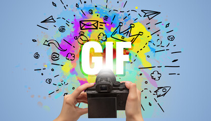 Close-up of a hand holding digital camera with abstract drawing and GIF inscription