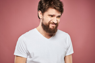 Fototapeta premium Emotional bearded man in white T-shirt discontent pink background