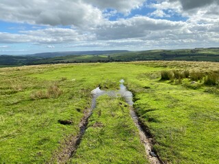 Fototapeta na wymiar Waterlogged track, on the moor top, with hills in the far distance in, Halton East, Skipton, UK