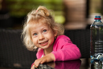 little girl drinking water at the table and smiling
