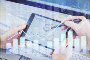 Double exposure of man's hands holding and using a phone and financial chart drawing. Market analysis concept.