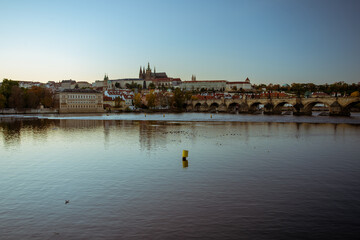 Fototapeta premium view of the Vltava river and Prague Castle St. Vitus Cathedral and Charles Bridge in the center of Prague at sunset. there are reflections on the river surface and the sky is illuminated by the sun