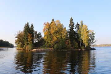 picturesque autumn landscape with an small island in the middle of the lake, where different types of tall trees grow