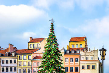 New Year Christmas tree decorated with illumination ornaments by multicolored architecture of old town market square in Warsaw, Poland