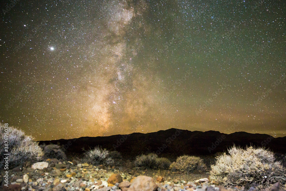 Wall mural the milky way galaxy rising over the desert landscape in death valley national park (california).