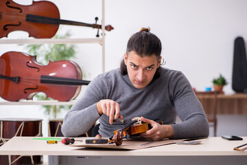 Young male repairman repairing violin