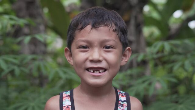 Close Up Video Portrait of a Handsome Cute Toothless Asian Filipino Kid Smiling into the Camera from the Rural Village in the Philippines with Extreme Happiness