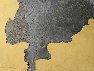 Mustard yellow paint peeling from a grey grunge concrete wall, creating a background with an abstract design