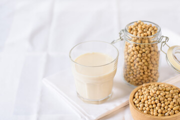 Soy milk in glass and soy bean on white background