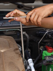 An engine mechanic in a car repair shop uses a  T-wrench to tighten the nut.