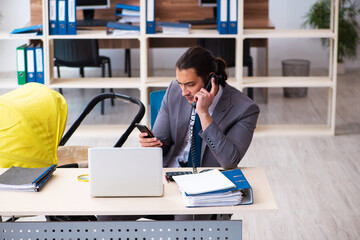 Young male employee looking after newborn at workplace