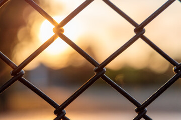 sunset through chain link fence with blue sky - Powered by Adobe