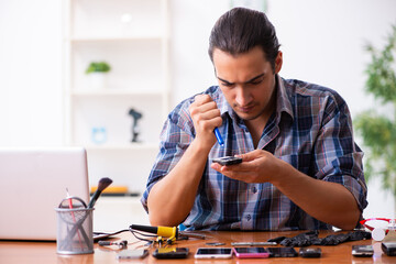 Young male technician repairing mobile phone