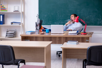 Young male teacher in front of green board