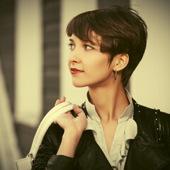 Happy young fashion woman in leather jacket with pixie hair style