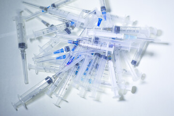 Close up of many used syringes on a white background. Mass vaccination concept. Mass immunization. Anti-virus vaccine trials. Covid-19 cure trials concept. Vaccine scientific research concept