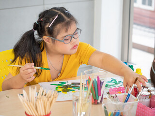 The cute little girl down syndrome learning about drawing and painting while enjoying development...