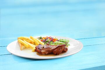 Chicken steak with grilled bread and salad plate on blue table.