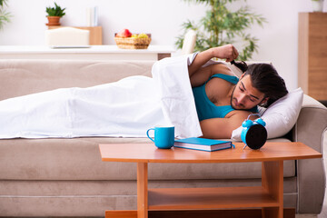 Young man lying on the sofa in time management concept