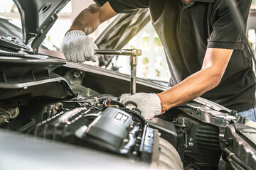 Close-up hands of auto mechanic are using the wrench to repair a car engine in auto car garage....