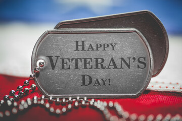 Worn US American dog tags on USA flag with Happy Veteran's Day engraved text