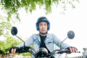 Fototapeta premium Young Vietnamese motorcyclist concentrated on road when riding fast in the city