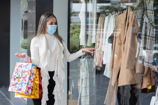 Mujer con tapabocas en centro comercial, mujer con tapabocas de compras con paquetes en man, compras en epocas de pandemia
