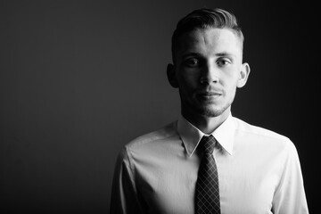 Portrait of young businessman against gray background