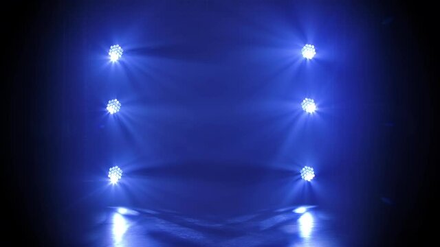 Stage blue floodlights shine during a live show concert, in a night club or party. Dark background. Studio spotlight or projector motion template.