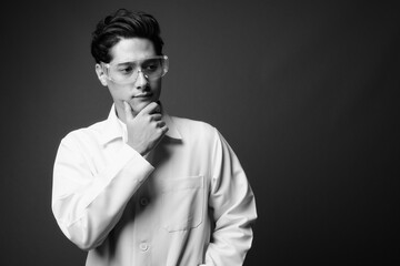 Portrait of young handsome man doctor as scientist with protective glasses