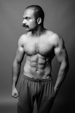 Muscular Indian man with mustache shirtless against gray background